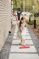 een weinig meisje met een borstel reinigt een pad Aan de straat in de binnenplaats foto