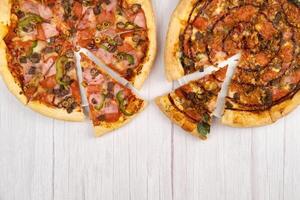 twee verschillend heerlijk groot pizza's Aan een licht houten achtergrond foto