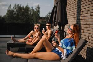 een gelukkig familie in zwemkleding zonnebaden in zomer Aan hun terras Aan zon bedden foto