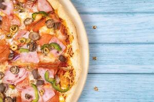 heerlijk groot pizza met kalfsvlees en champignons Aan een blauw houten achtergrond foto