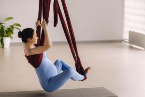 zwanger meisje. een vrouw doet yoga Aan een hangmat in de Sportschool. de concept van een gezond levensstijl, moederschap foto