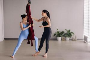 zwanger meisje. een vrouw met een trainer doet yoga in een hangmat in de Sportschool. de concept van een gezond levensstijl, moederschap foto