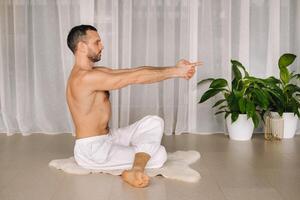 een Mens met een kaal torso doet yoga in een geschiktheid kamer. de concept van een gezond levensstijl foto