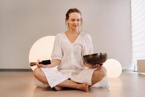 portret van een vrouw yoga leraar spelen een Tibetaans kom of het zingen een klok in de Sportschool gedurende een yoga terugtrekken foto