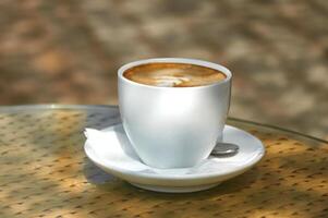 cappuccino in een wit kop Aan de tafel Aan een zonnig dag foto
