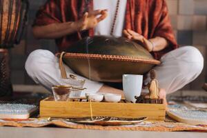 detailopname van een man's hand- spelen een modern musical instrument - de Orion tong trommel gedurende de thee ceremonie foto