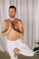 een Mens met een kaal torso doet yoga in een geschiktheid kamer. de concept van een gezond levensstijl foto