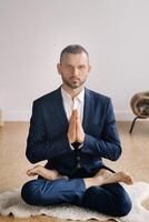 een Mens in een streng pak doet yoga terwijl zittend in een geschiktheid kamer foto