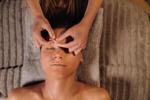 een schoonheidsspecialist meisje doet een gelaats en nek massage naar een meisje in de kantoor voor huid elasticiteit foto