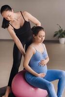 zwanger vrouw met een trainer gedurende geschiktheid klassen met een bal foto