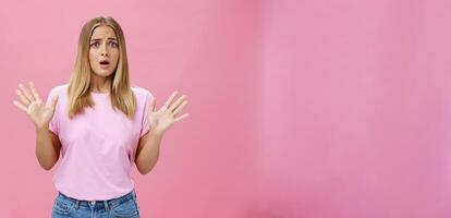 vrouw op zoek nerveus uitleggen met in paniek raken gebaren ze niet betrokken fronsen opening mond en hijgen gevoel bezorgd en bezorgd golvend handen over- borst poseren tegen roze muur foto