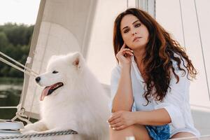 een gelukkig vrouw met een groot wit hond Aan een wit jacht in de zee foto