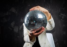 portret van een vrouw Holding een zilver disco bal. genomen in een foto studio.