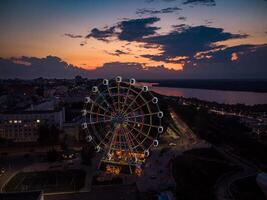 mooi zonsondergang over- de stad met een verlicht ferris wiel. foto