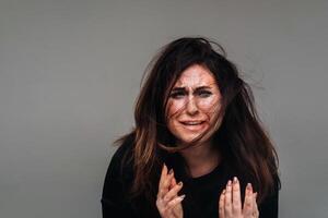 een gehavend vrouw in zwart kleren Aan een geïsoleerd grijs achtergrond. geweld tegen Dames foto