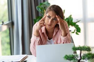 uitgeput zakenvrouw hebben een hoofdpijn in modern kantoor. creatief vrouw werken Bij kantoor bureau gevoel moe. benadrukt gewoontjes bedrijf vrouw gevoel hoofd pijn terwijl overbelasting Aan bureaublad computer. foto