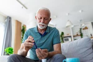 volwassen Mens testen voor hoog bloed suiker. Mens Holding apparaat voor meten bloed suiker, aan het doen bloed suiker testen. senior Mens controle bloed suiker niveau door glucometer en test streep Bij huis foto