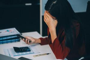 Aziatisch Dames zijn benadrukt terwijl werken Aan laptop, moe Aziatisch zakenvrouw met hoofdpijn Bij kantoor, gevoel ziek Bij werk, kopiëren ruimte foto