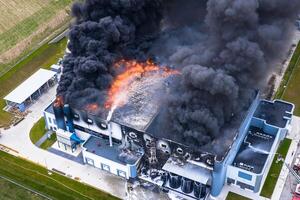 antenne visie van verbrand industrieel magazijn of logistiek centrum gebouw na groot brand met reusachtig rook van verbrand dak foto