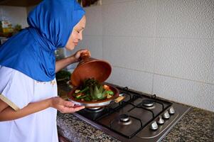 Marokkaans huisvrouw Koken groenten in tajine klei schotel Bij huis keuken foto