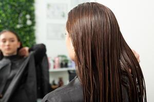 portret van een mooi vrouw met lang bruin Rechtdoor haar- in een schoonheid salon. foto