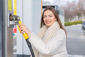 jong vrouw tanken auto met benzine Bij gas- station. eco brandstof concept. de concept van milieuvriendelijk vriendelijk vervoer. foto