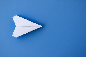 top visie van een wit papier vliegtuigen origami vliegend Aan blauw achtergrond foto