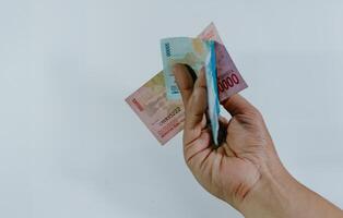 Indonesisch munteenheid. hand- Holding 100.000 en 50.000 roepia bankbiljetten Aan een wit achtergrond. foto