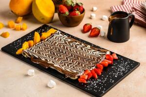 nutella chocola crêpe gegarneerd met aardbei en mango plak geserveerd in schotel geïsoleerd Aan tafel top visie van cafe toetje foto