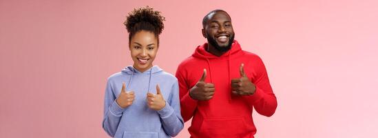 het beste vrienden ondersteuning uw keuze. portret trots tevreden mooi Afro-Amerikaans Mens vrouw tonen camera duimen omhoog glimlachen breed juichen leuk vinden geweldig aankoop, staand roze achtergrond foto