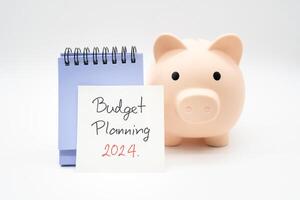 begroting planning 2024 tekst bericht door hand- schrijven Aan papier Opmerking, kalender en varkentje bank. begroting planning concept. foto