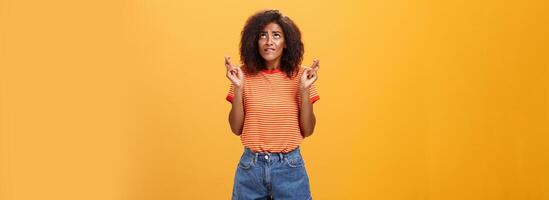 god het belangrijk naar mij. nerveus elegant en aantrekkelijk slank met een donkere huid vrouw met gekruld kapsel bijten lager lip op zoek omhoog, fronsen kruispunt vingers voor mooi zo geluk maken wens aan het wachten resultaat foto