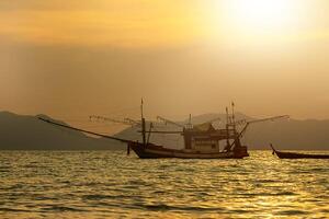 silhouetten van visvangst boot Aan de zee foto