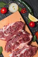 rauw varkensvlees vlees Aan houten snijdend bord Bij keuken tafel voor Koken varkensvlees steak geroosterd of gegrild met ingrediënten kruid en specerijen , vers varkensvlees. foto