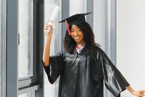 vrolijke Afro-Amerikaanse afgestudeerde student met diploma in haar hand foto