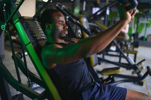 gemotiveerd jong zwart sportman hebben training Aan roeien machine foto