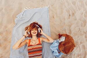 zomer strand vakantie. blij glimlachen vrouw omarmen vrijheid en natuur terwijl zonnen Aan zanderig foto