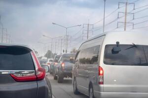 achterzijde kant van grijs auto sluiten omhoog Aan staart licht. verkeer jam met beurt Aan rem licht. auto's Aan de weg rubriek naar de doel van de reis. naast weg met elektrisch zwembaden. onder de dag lucht. foto