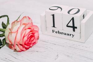 roze thee roos met hart vormig roze mousse taart en februari 14 kalender. foto
