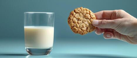 ai gegenereerd detailopname van een hand- Holding een koekje, glas van melk. reeks tegen een levendig blauw achtergrond, helder verlichting verbetert de verwachting van de dompelen moment. foto