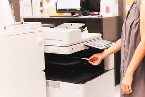 vrouw officier Trekken het drukken papier document uit van functioneel kantoor printer. foto