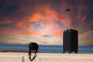 koffer en zak zijn staand Aan een strand met een zonsondergang in de background.travel en vakantie concept foto