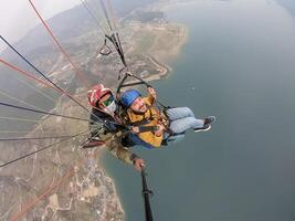 paragliden in de bergen, de twee personen Aan de top van de berg, de parachutisten zijn vliegend met een parachute foto