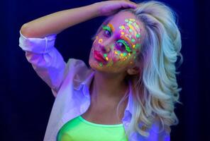 portret van een vrouw met geschilderd gezicht, vrouw met uv bedenken in studio, portret van een vrouw in carnaval masker, de vrouw is versierd in een ultraviolet poeder foto