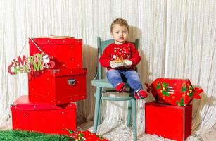 de weinig kind spelen met Kerstmis decoraties in studio, weinig kind met Kerstmis bal foto