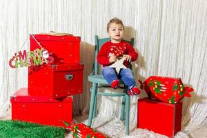 de weinig kind spelen met Kerstmis decoraties in studio, weinig kind met Kerstmis bal foto