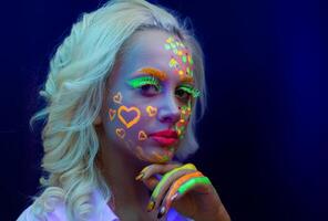 portret van een vrouw met geschilderd gezicht, vrouw met uv bedenken in studio, portret van een vrouw in carnaval masker, de vrouw is versierd in een ultraviolet poeder foto