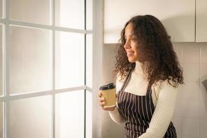 Latijnse vrouw die koffie drinkt in de keuken foto