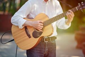 Mens spelen elektro akoestisch gitaar Bij buitenshuis evenement, vrij musical prestatie van straat musicus foto