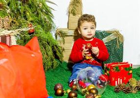 de weinig kind spelen met Kerstmis decoraties in studio, weinig kind met Kerstmis bal foto